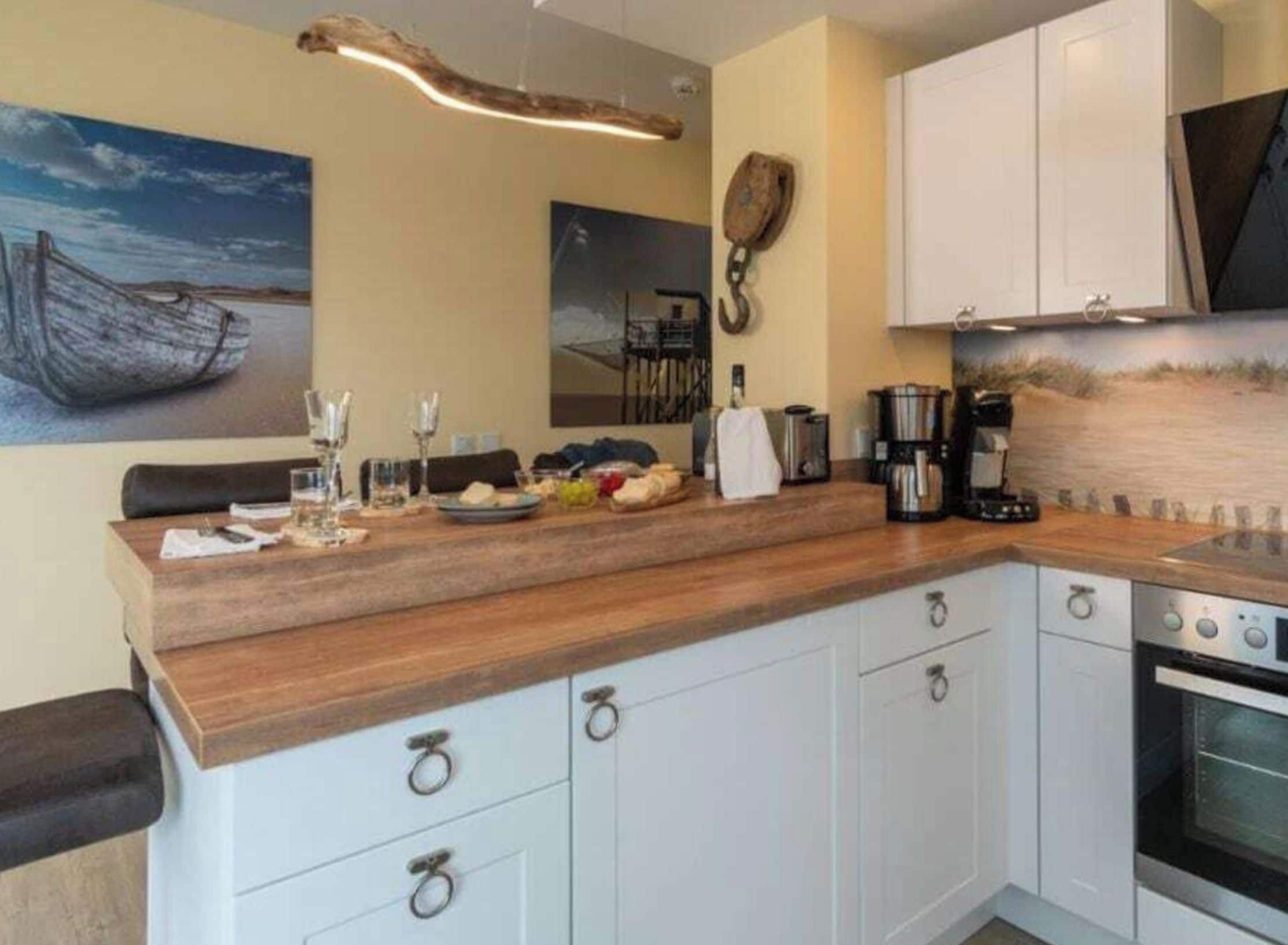 A modern kitchen with white cabinets, a wooden countertop, and a coffee machine.