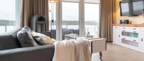 En moderne stue med sofa, sofabord og et fjernsyn ophængt på væggen.