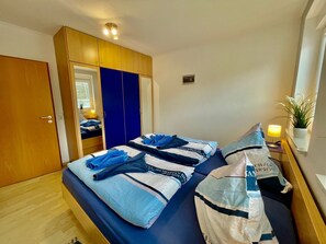 Ein Schlafzimmer mit einem Bett, einem Kleiderschrank und einem Nachttisch mit einer Lampe.
