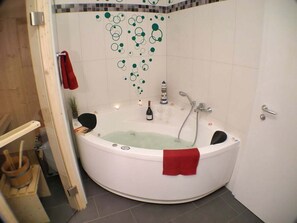 Ein Badezimmer mit freistehender Badewanne, einer Dusche und einer gefliesten Wand mit kreisförmigen Mustern.