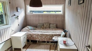 Una camera da letto compatta con un letto, comodino, lampada e una finestra.