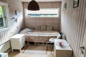 Une chambre à coucher de taille réduite, comprenant un lit, une table de chevet, une lampe et une fenêtre.