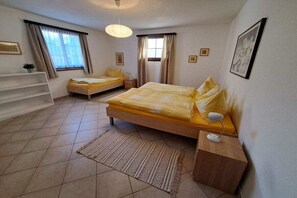 Una camera da letto con due letti, una scrivania, una sedia, una finestra con tende e un lampadario.