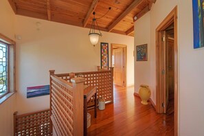 A wooden staircase with a railing, a hanging light fixture, and a door leading to another room. - Hilltop Ocean Views - Twin Outdoor Baths & Pool (Nelson)