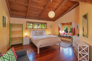 A bedroom with a wooden ceiling, a bed with a white bedspread, a nightstand, a dresser, and a window with curtains. - Hilltop Ocean Views - Twin Outdoor Baths & Pool (Nelson)