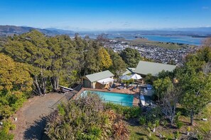 Ein Wohnhaus mit Pool, überdachter Terrasse und Blick auf eine Stadt und ein Gewässer.