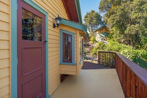 Ein Haus mit Veranda, einer Holzterrasse und einer Treppe zu einer zweiten Ebene.