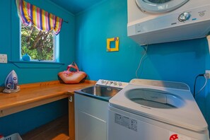 A laundry room with a washing machine, a dryer, and a window with curtains. - Hilltop Ocean Views - Twin Outdoor Baths & Pool (Nelson)