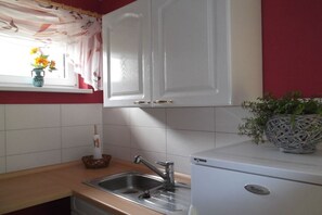Eine Küche mit weißen Schränken, einer Edelstahl-Spüle und einem weißen Kühlschrank.