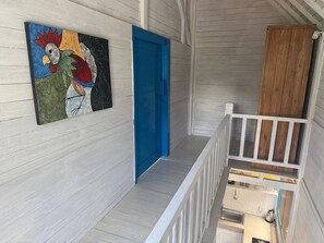 Un interior de madera con una puerta azul, una barandilla blanca y una zona de cocina con fregadero y armarios.