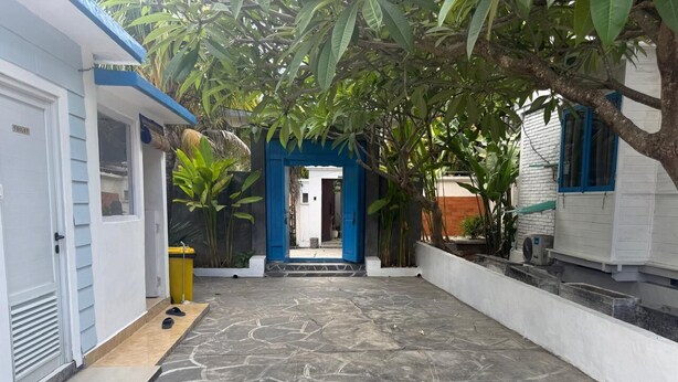 Ein Innenhof mit einem gemusterten Betonboden, einem blauen Bogen und einem weißen Gebäude mit einer blauen Tür.