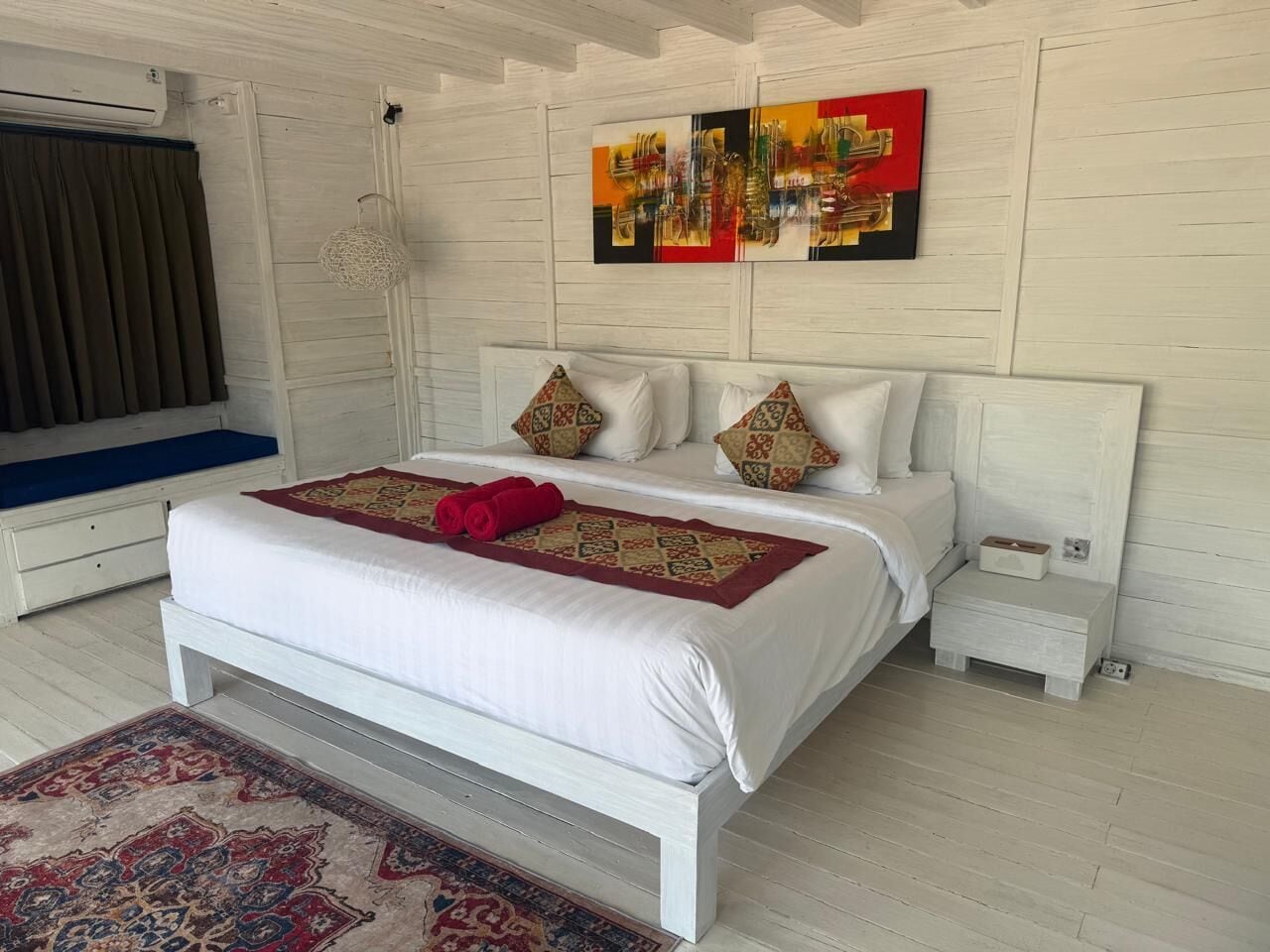 Een slaapkamer met een bed, een nachtkastje, een wandairconditioner en een decoratief wandobject.