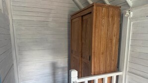 Ein Holzkabinett vor einer weißen Wand mit Wandverkleidung und einem weißen Geländer.