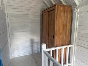 Ein Holzkabinett vor einer weißen Wand mit Wandverkleidung und einem weißen Geländer.