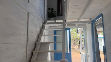 Eine Treppe mit weißen Geländern führt zu einem Außenbereich mit einer blauen Tür.