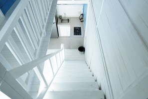 Una escalera que lleva a una zona de cocina con un lavamanos, una estufa y un cubo de basura.