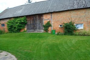 A brick building with a large wooden door and a metal roof. - Holiday apartment with 2 bedrooms (Mirow\/ Ortsteil Babke)