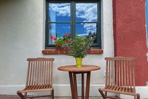Eine hölzerne Bank und ein Tisch mit einem Blumentopf vor einem Fenster.