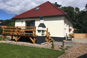 Ein eingeschossiges Gebäude mit rotem Ziegeldach, Schornstein und kleinem Fenster.