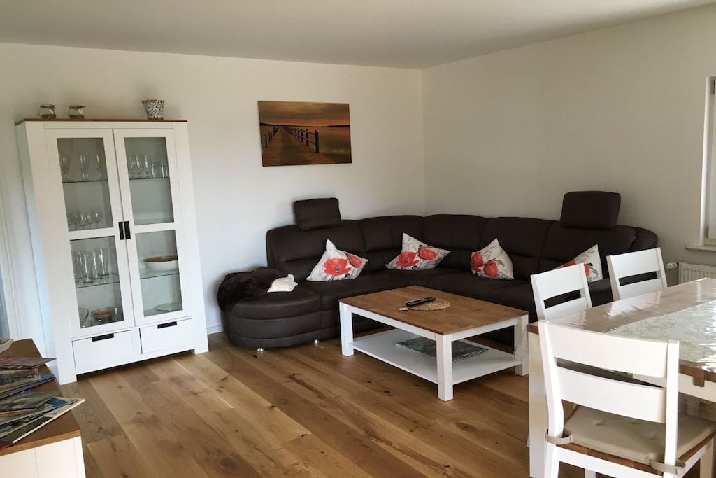 Una sala de estar con un sofá marrón oscuro, un mueble blanco y una mesa de centro.