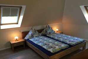 A bedroom with a bed, two bedside tables, a window, and a nightstand with a lamp. - Holiday home at Eichenfleck (Seedorf)