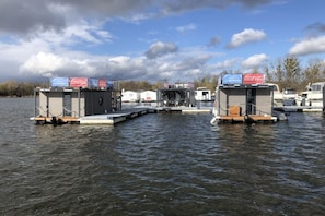 Una estructura flotante con varias cabañas, barcos amarrados y cielo despejado.