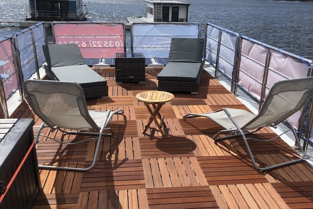 A deck with two lounge chairs, a small round table, and a view of the water.