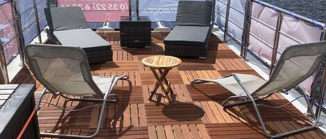 A deck with two lounge chairs, a small round table, and a view of the water.
