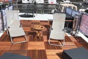 A boat deck with two lounge chairs, a small wooden table, and a metal grill. - myHolidayBoat Krimnicksee (Königs Wusterhausen)
