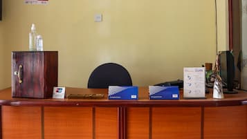 Mostrador de recepción con detalles de madera, una silla, un monitor de computadora y varios carteles y certificados en la pared.
