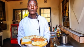 Un chef sostiene un plato con diferentes alimentos en una cocina.