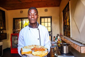 A chef holding a plate with various foods in a kitchen setting.