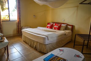 Habitación de hotel con cama, mesita de noche, una silla y una ventana con cortinas.