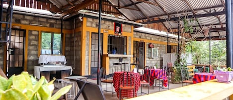 An outdoor cafe with tables and chairs, a coffee station, and a stone wall.