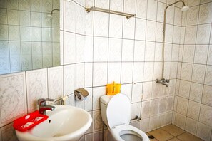 Et badeværelse med toilet, vask og bruser.