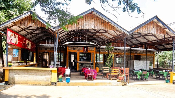 A rustic building with a bar area, outdoor seating, and a covered entrance. - Rainbow Executive Lodge (Boma Ng'ombe)