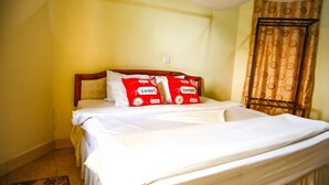 Una cama con ropa de cama blanca y dos almohadas rojas con el texto 'sweet home'.