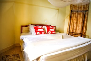 A bed with white bedding and two red pillows with 'sweet home' text.
