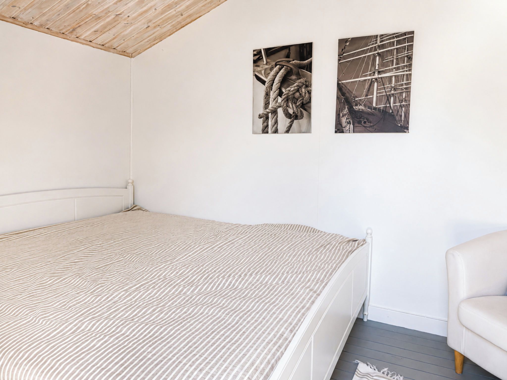 Un dormitorio con una cama individual, un cabecero blanco y dos fotografías blanco y negro en la pared.