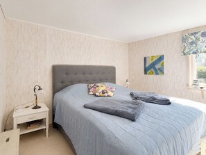 A bedroom with a large bed, a nightstand, a lamp, and a window with a view. - Jennys Pärla by Interhome (Haverdal)