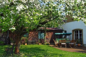 A garden with a patio, a wooden table, chairs, and a bench. - under the old apple tree (Unterspreewald OT Leibsch)