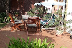 A patio with a table and chairs, surrounded by potted plants and a wooden fence. - under the old apple tree (Unterspreewald OT Leibsch)