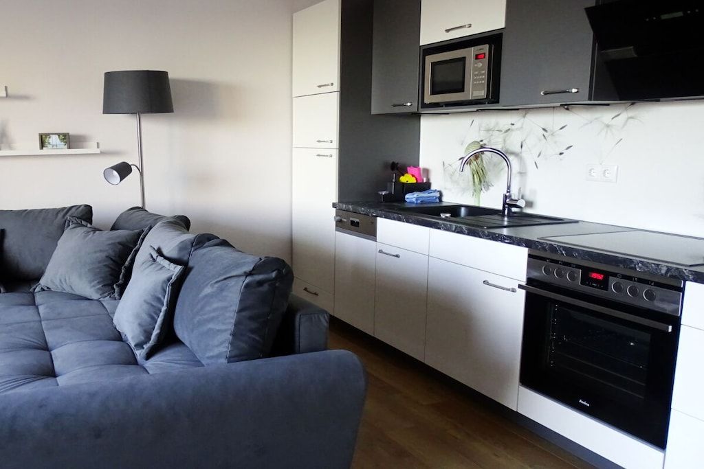 Una cocina moderna con armarios blancos, una estufa negra y un microondas sobre la encimera.