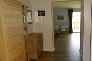 A hallway with a wooden wardrobe, a small wooden cabinet, and a dining area with a table and chairs. - On the Wünnow river with a boat dock (Röbel)