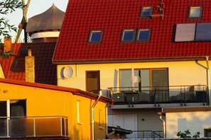 Ein mehrstöckiges Gebäude mit rotem Dach, gelber Fassade und einem Balkon im oberen Geschoss.