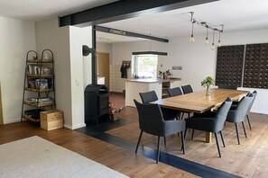 A modern kitchen with a central island, a dining area with a wooden table and chairs, and a bookshelf. - "the house by the lake" (Malchow)