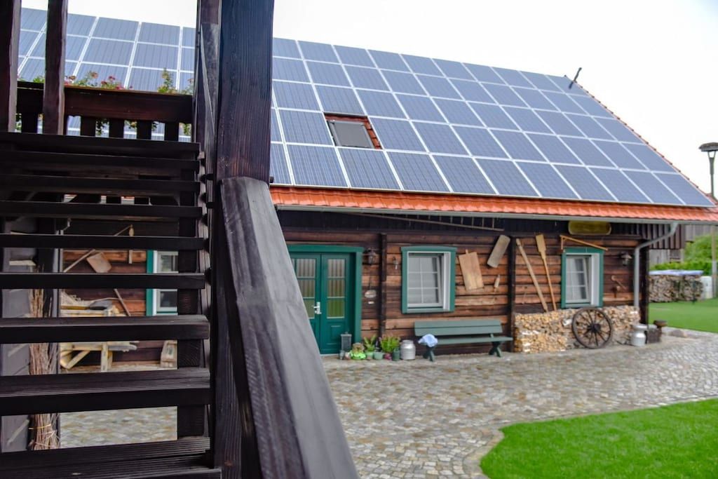 Una cabaña de madera con techo inclinado, una puerta verde y un patio empedrado de piedra.