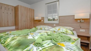 Een slaapkamer met een bed, een raam met gordijnen, een kledingkast en bedlampen.