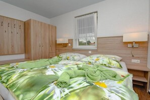 Una camera da letto con un letto, una finestra con tende, un armadio e abat-jour.