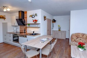 A modern kitchen with a central island, built-in oven, and white cabinetry. - Holiday apartment with 2 bedrooms (Märkische Heide OT Biebersdorf)